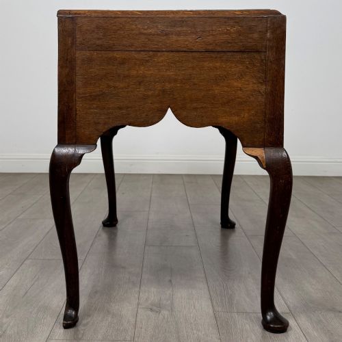 fig 6. An 18th-century Georgian oak side table featuring three drawers with brass drop handles, an arched apron, and cabriole legs.