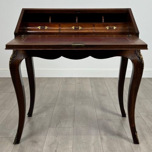 fig 1. A 19th-century French rosewood bureau de dame with floral marquetry inlay on the hinged top and apron, raised on cabriole legs with gilt-bronze ormolu mounts.
