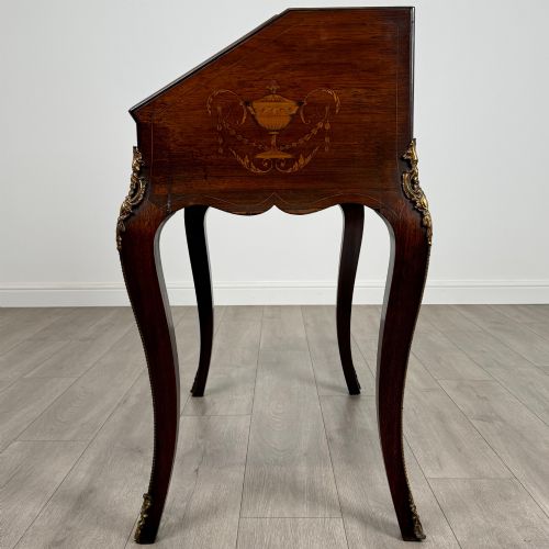 fig 3. A 19th-century French rosewood bureau de dame with floral marquetry inlay on the hinged top and apron, raised on cabriole legs with gilt-bronze ormolu mounts.