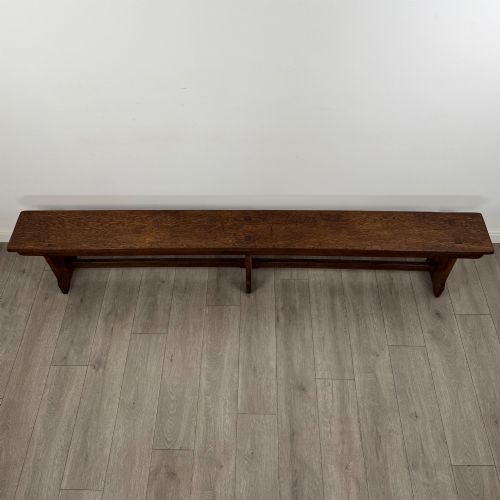 fig 7. A long 19th-century Georgian oak tavern bench featuring a smooth plank seat supported by three sturdy slab legs and a full-length lower stretcher.