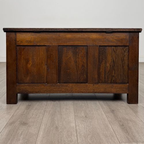 fig 4. A rectangular dark oak blanket box featuring a hinged top lid, panelled front sections, and carved arch motifs along the upper frieze.