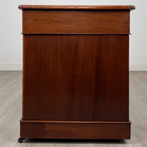 fig 2. A 19th-century Victorian mahogany pedestal desk featuring nine drawers with circular brass knobs and keyholes, supported by twin plinth bases on casters.