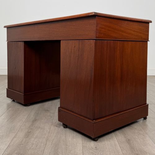 fig 5. A 19th-century Victorian mahogany pedestal desk featuring nine drawers with circular brass knobs and keyholes, supported by twin plinth bases on casters.