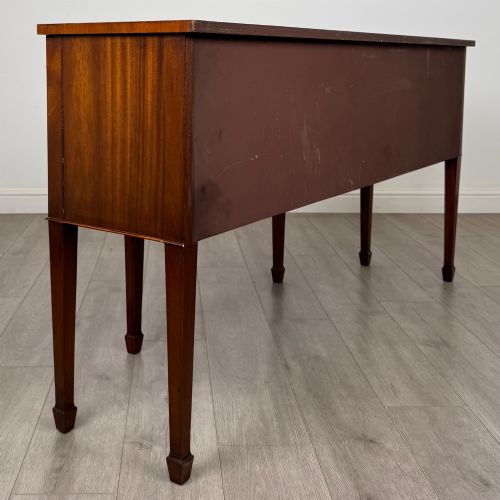 fig 4. A 19th-century mahogany bow-front sideboard with central drawers, side cupboards, and tapered square legs.