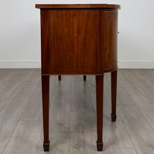 fig 7. A 19th-century mahogany bow-front sideboard with central drawers, side cupboards, and tapered square legs.