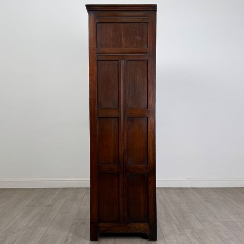 fig 3. A tall single-door dark oak Edwardian wardrobe featuring a carved upper linenfold panel and decorative iron hinges.