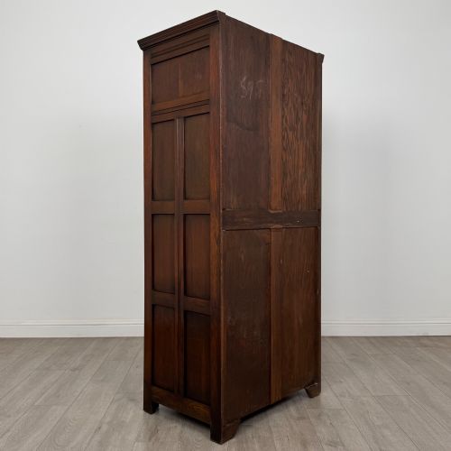fig 4. A tall single-door dark oak Edwardian wardrobe featuring a carved upper linenfold panel and decorative iron hinges.