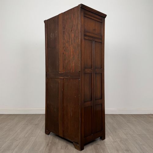 fig 6. A tall single-door dark oak Edwardian wardrobe featuring a carved upper linenfold panel and decorative iron hinges.