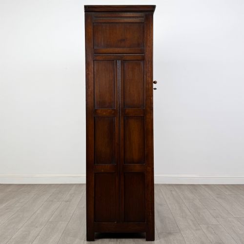 fig 7. A tall single-door dark oak Edwardian wardrobe featuring a carved upper linenfold panel and decorative iron hinges.