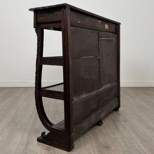 fig 3. A 19th-century dark oak open bookcase featuring hand-carved frieze foliage, a central mask motif, and three tiers of open shelving.