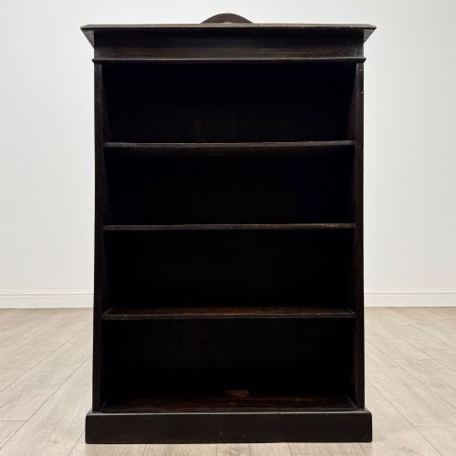 fig 1. An Edwardian dark-stained oak open bookcase featuring four shelf tiers containing red leather-bound books against a white background.