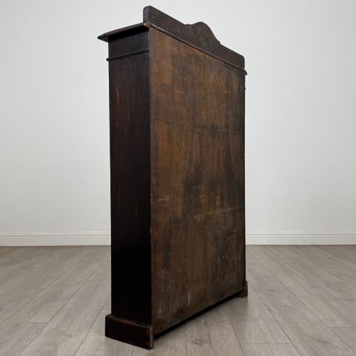 fig 4. An Edwardian dark-stained oak open bookcase featuring four shelf tiers containing red leather-bound books against a white background.
