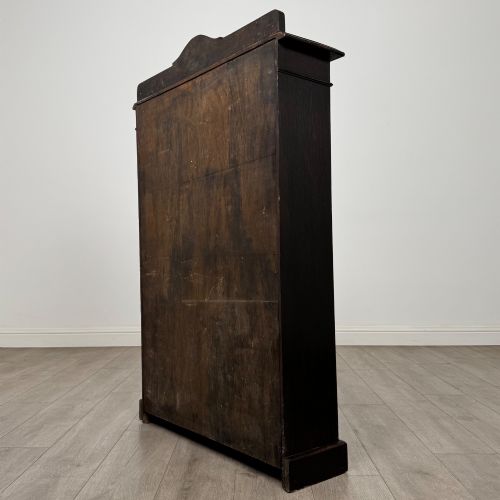fig 6. An Edwardian dark-stained oak open bookcase featuring four shelf tiers containing red leather-bound books against a white background.