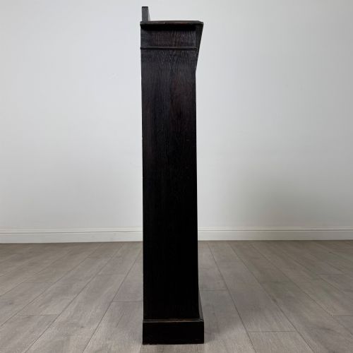 fig 7. An Edwardian dark-stained oak open bookcase featuring four shelf tiers containing red leather-bound books against a white background.