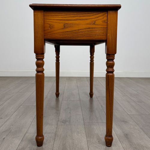 fig 2. A 20th-century warm brown oak writing table featuring two frieze drawers with ring drop handles and four turned legs.