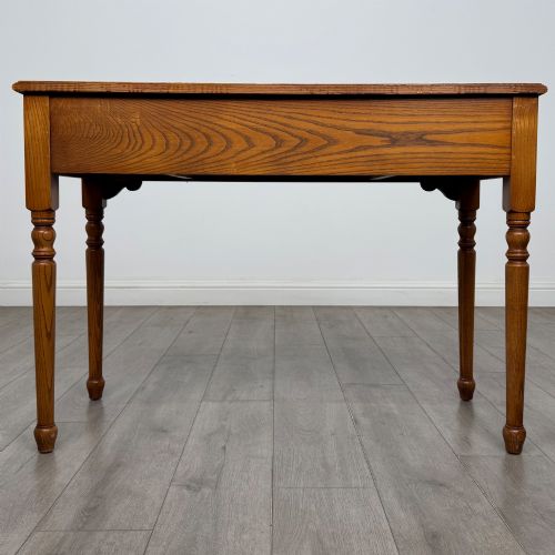 fig 4. A 20th-century warm brown oak writing table featuring two frieze drawers with ring drop handles and four turned legs.