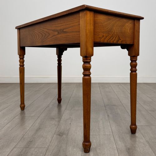 fig 5. A 20th-century warm brown oak writing table featuring two frieze drawers with ring drop handles and four turned legs.