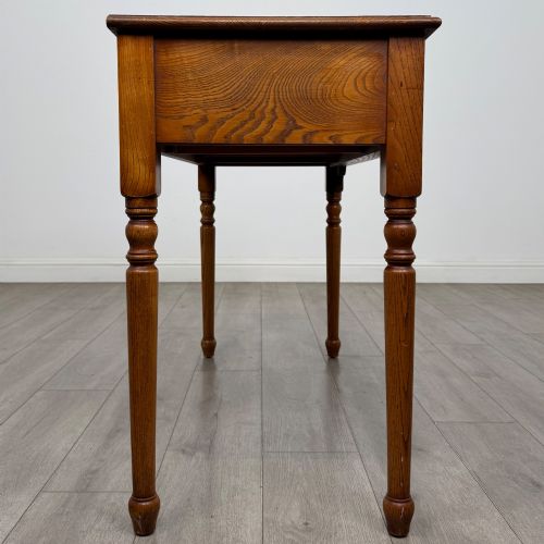 fig 6. A 20th-century warm brown oak writing table featuring two frieze drawers with ring drop handles and four turned legs.
