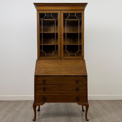 fig 1. An Edwardian oak bureau bookcase with a two-door upper glazed display cabinet, a sloping drop-front desk, three wide drawers, and cabriole legs.