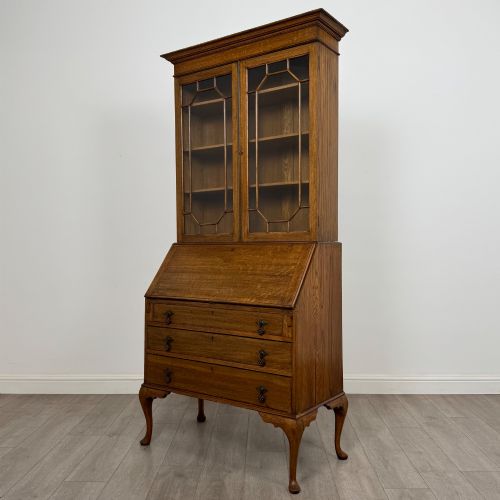fig 3. An Edwardian oak bureau bookcase with a two-door upper glazed display cabinet, a sloping drop-front desk, three wide drawers, and cabriole legs.