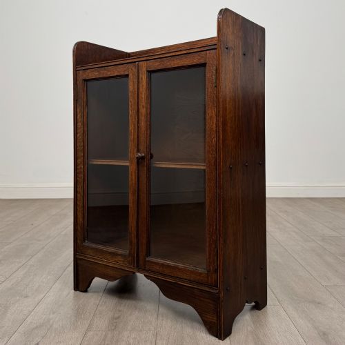 fig 2. An early 20th-century dark oak display cabinet featuring twin glazed doors, an interior shelf, and a gallery top.