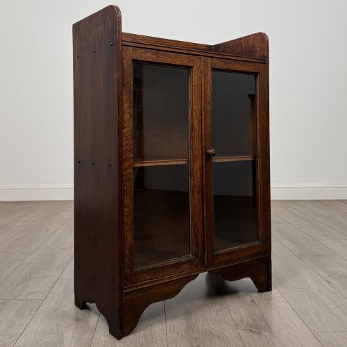 fig 8. An early 20th-century dark oak display cabinet featuring twin glazed doors, an interior shelf, and a gallery top.