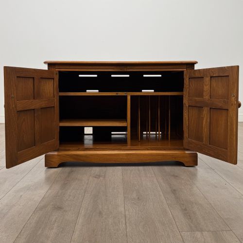 fig 1. A two-door golden oak storage cupboard featuring geometric panelled doors, turned timber knobs, and a low plinth base.