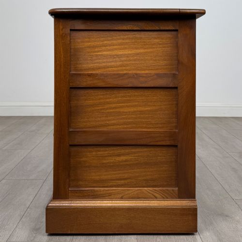 fig 3. A two-door golden oak storage cupboard featuring geometric panelled doors, turned timber knobs, and a low plinth base.