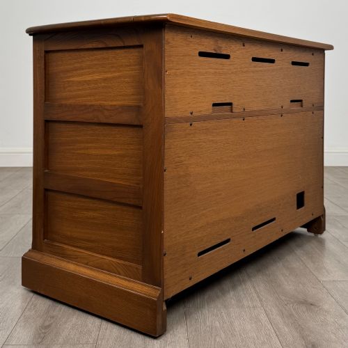 fig 4. A two-door golden oak storage cupboard featuring geometric panelled doors, turned timber knobs, and a low plinth base.