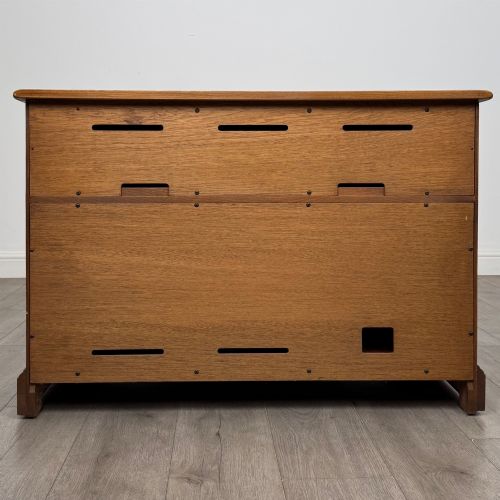 fig 5. A two-door golden oak storage cupboard featuring geometric panelled doors, turned timber knobs, and a low plinth base.