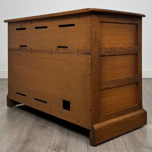 fig 6. A two-door golden oak storage cupboard featuring geometric panelled doors, turned timber knobs, and a low plinth base.