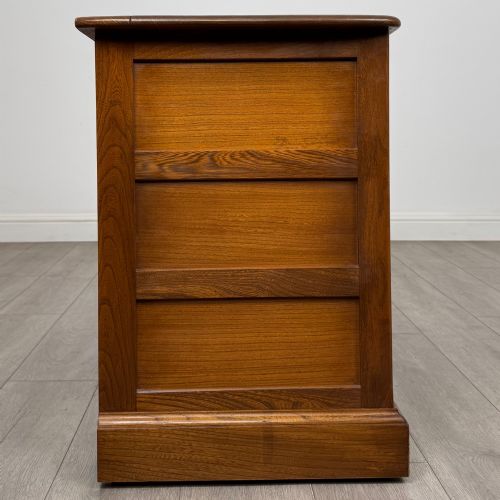 fig 7. A two-door golden oak storage cupboard featuring geometric panelled doors, turned timber knobs, and a low plinth base.