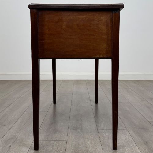 fig 2. An Edwardian mahogany writing table featuring three drawers with satinwood crossbanding, brass ring pull handles, and square tapered legs.
