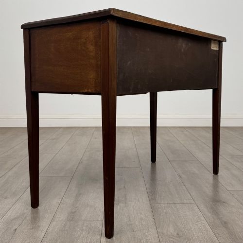 fig 3. An Edwardian mahogany writing table featuring three drawers with satinwood crossbanding, brass ring pull handles, and square tapered legs.