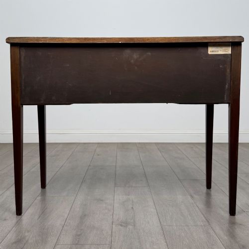 fig 4. An Edwardian mahogany writing table featuring three drawers with satinwood crossbanding, brass ring pull handles, and square tapered legs.