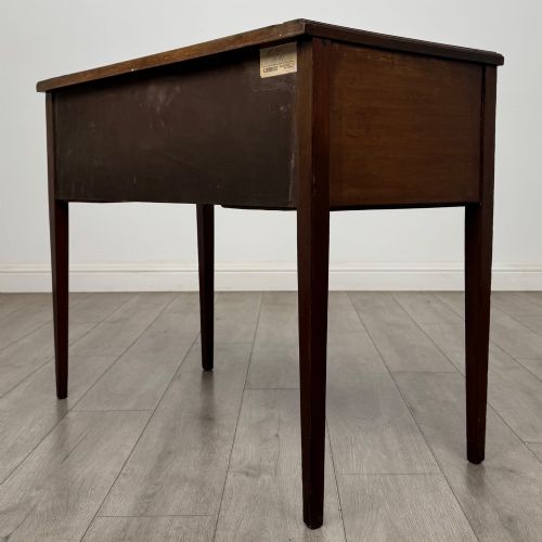 fig 5. An Edwardian mahogany writing table featuring three drawers with satinwood crossbanding, brass ring pull handles, and square tapered legs.