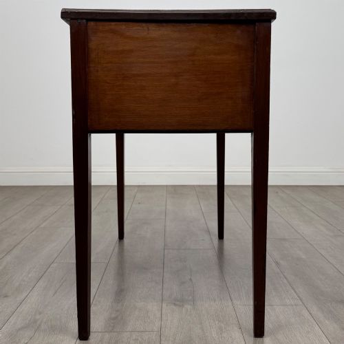fig 6. An Edwardian mahogany writing table featuring three drawers with satinwood crossbanding, brass ring pull handles, and square tapered legs.