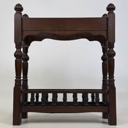 fig 4. An Edwardian dark oak umbrella stand featuring four turned corner posts topped with finials, a shaped upper crossbar, and a lower spindle gallery enclosing a drip tray.