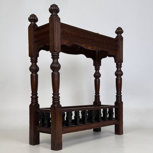 fig 7. An Edwardian dark oak umbrella stand featuring four turned corner posts topped with finials, a shaped upper crossbar, and a lower spindle gallery enclosing a drip tray.