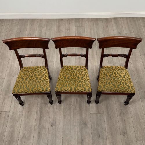 fig 7. A set of six 19th-century William IV mahogany dining chairs featuring turned front legs, curved back rails, and green patterned fabric seats.