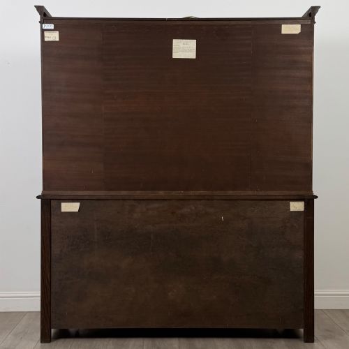 fig 6. A dark oak display cabinet with a leaded glass central upper cupboard, flanked by open shelves, set atop a lower unit with multiple drawers and carved cupboard doors.