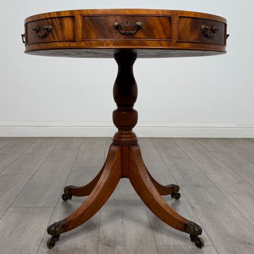 fig 2. A small Regency style circular mahogany drum table featuring frieze drawers with brass handles, supported by a central turned pedestal and reeded splayed legs on brass castors.