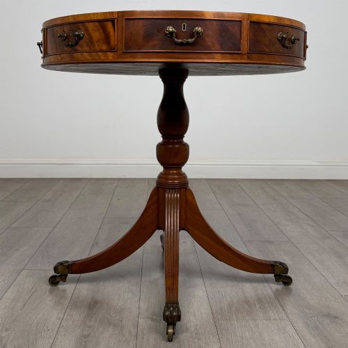 fig 3. A small Regency style circular mahogany drum table featuring frieze drawers with brass handles, supported by a central turned pedestal and reeded splayed legs on brass castors.