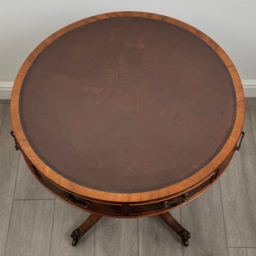 fig 4. A small Regency style circular mahogany drum table featuring frieze drawers with brass handles, supported by a central turned pedestal and reeded splayed legs on brass castors.