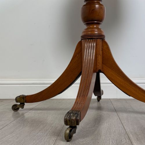 fig 5. A small Regency style circular mahogany drum table featuring frieze drawers with brass handles, supported by a central turned pedestal and reeded splayed legs on brass castors.