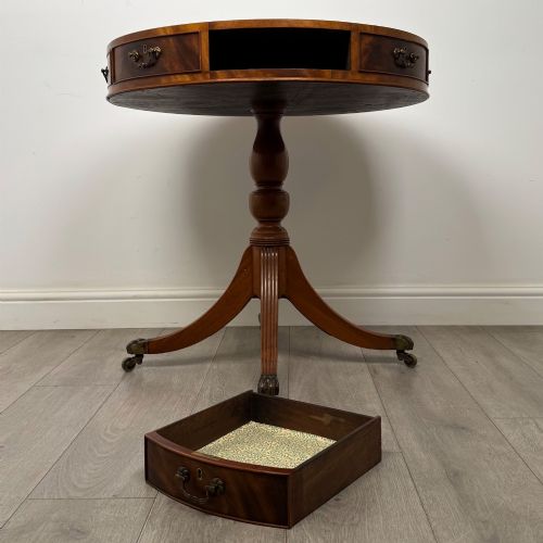 fig 6. A small Regency style circular mahogany drum table featuring frieze drawers with brass handles, supported by a central turned pedestal and reeded splayed legs on brass castors.