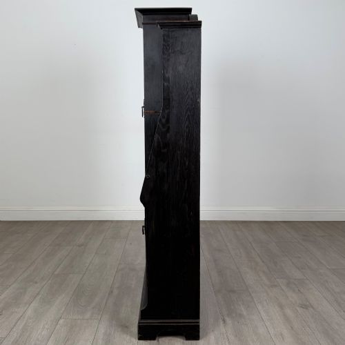 fig 4. An ebonised oak bureau bookcase featuring an asymmetrical design with a glazed door cabinet, a slanted fall-front writing surface, open shelving, and a heart cutout crest.