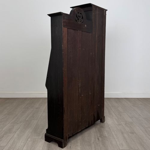 fig 5. An ebonised oak bureau bookcase featuring an asymmetrical design with a glazed door cabinet, a slanted fall-front writing surface, open shelving, and a heart cutout crest.