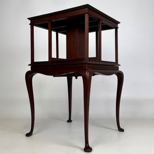 fig 3. A dark mahogany revolving bookcase featuring a two-tier rotating upper section supported by slender cabriole legs ending in pad feet.