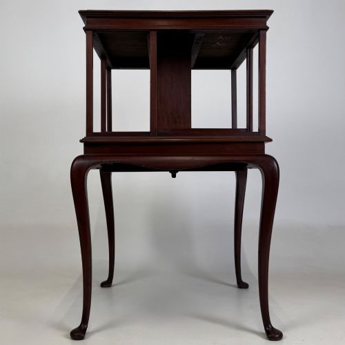 fig 4. A dark mahogany revolving bookcase featuring a two-tier rotating upper section supported by slender cabriole legs ending in pad feet.